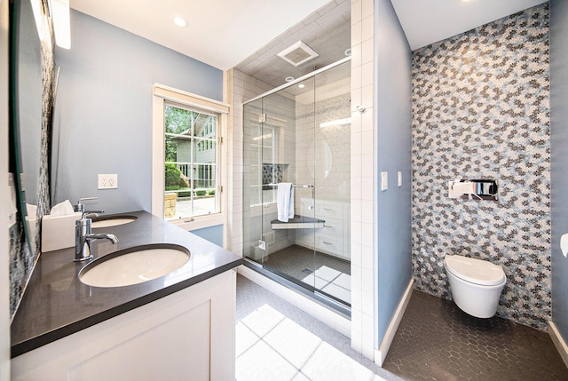 bathroom featuring toilet, a stall shower, double vanity, and a sink