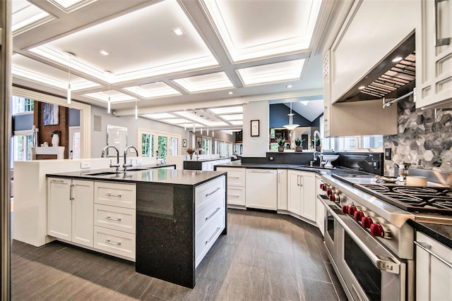 kitchen featuring coffered ceiling, a sink, double oven range, dark countertops, and custom range hood