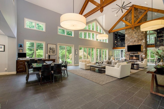 living room featuring high vaulted ceiling, a stone fireplace, beamed ceiling, and baseboards