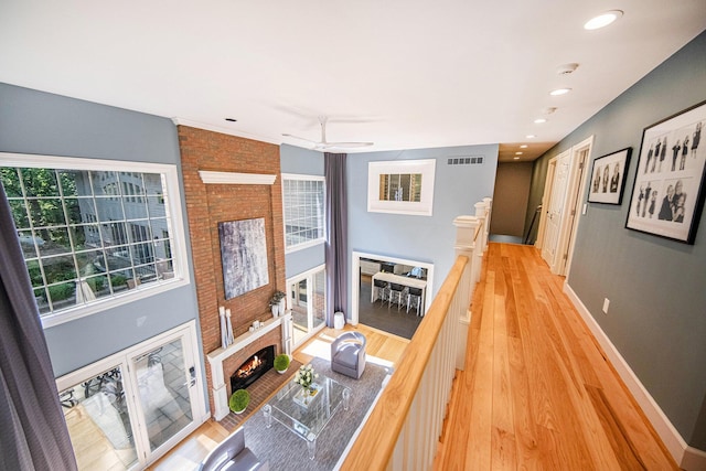 living room featuring visible vents, baseboards, light wood-style flooring, a lit fireplace, and recessed lighting