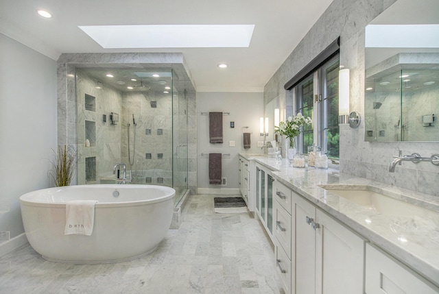 full bath with marble finish floor, double vanity, a skylight, and a sink