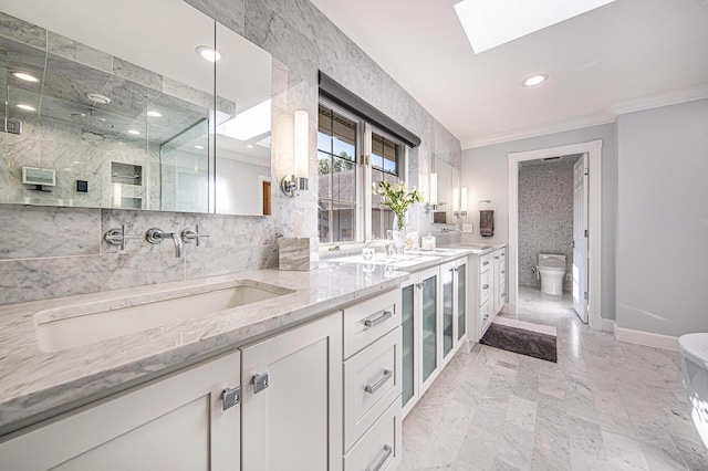 bathroom with double vanity, a skylight, ornamental molding, a shower stall, and a sink