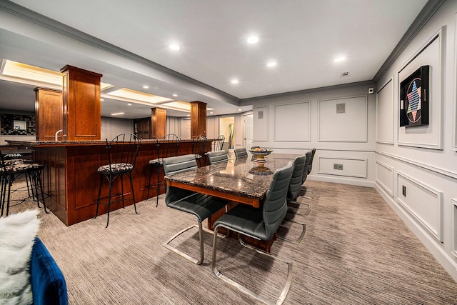 dining room featuring recessed lighting, light carpet, crown molding, a decorative wall, and ornate columns