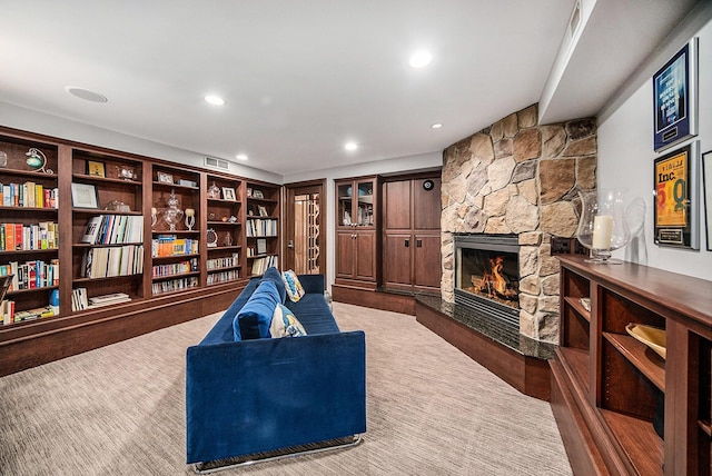 living area featuring recessed lighting, visible vents, and a stone fireplace