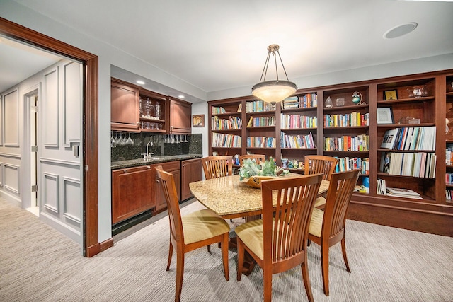 dining space featuring light carpet and wet bar