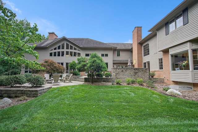 rear view of house with a yard, a chimney, and a patio