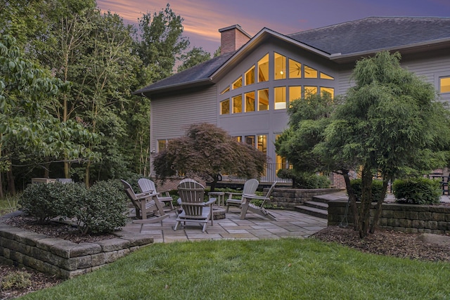 back of house with a patio area, a chimney, and a lawn