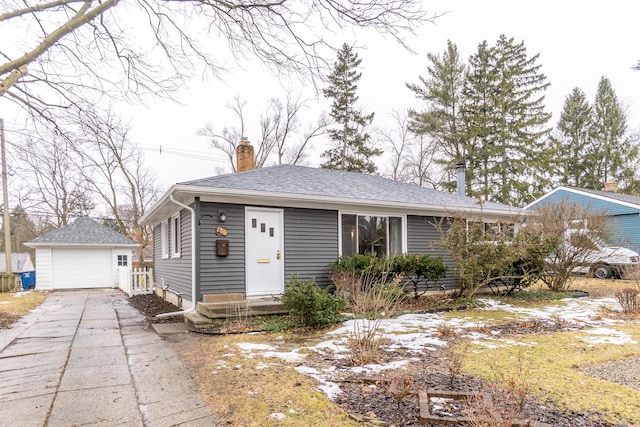 view of front facade featuring a shingled roof, a chimney, an outdoor structure, and a detached garage