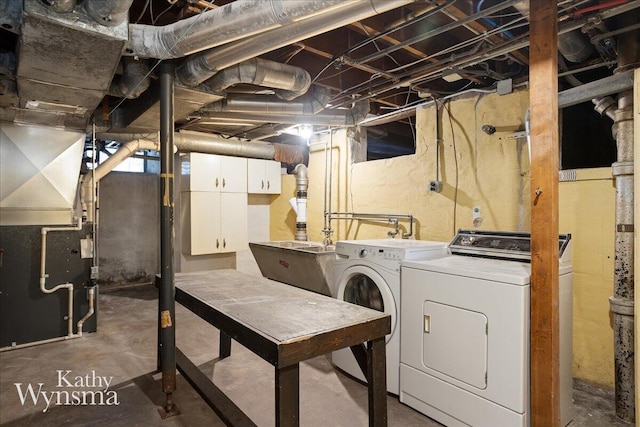 washroom with heating unit, cabinet space, washing machine and dryer, and a sink