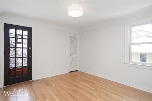 unfurnished room with light wood-style flooring, visible vents, and a wealth of natural light