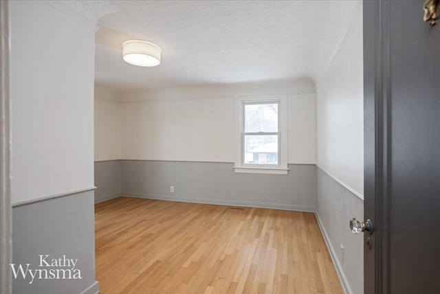 empty room featuring crown molding, a textured ceiling, and wood finished floors