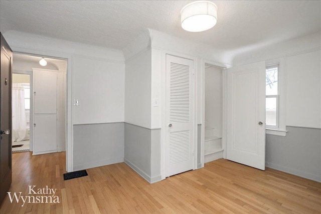 empty room featuring baseboards, light wood-style flooring, and a textured ceiling