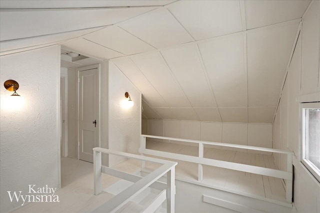 additional living space featuring lofted ceiling and a textured wall