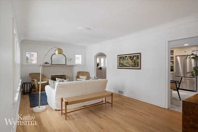 bedroom featuring light wood-style floors, high end fridge, visible vents, and arched walkways