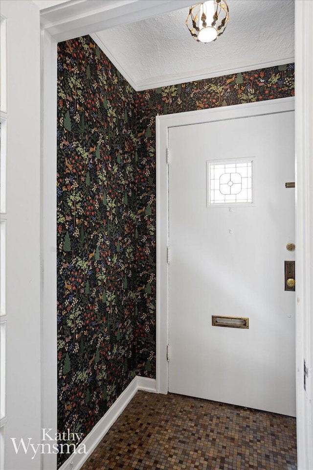 interior space with ornamental molding, a textured ceiling, and wallpapered walls