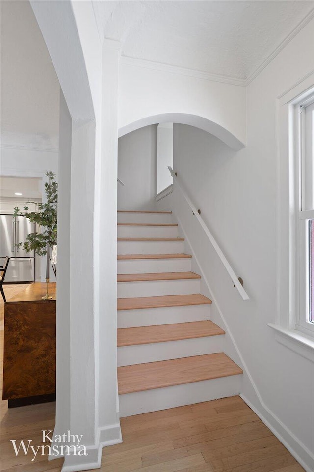 staircase featuring crown molding and wood finished floors