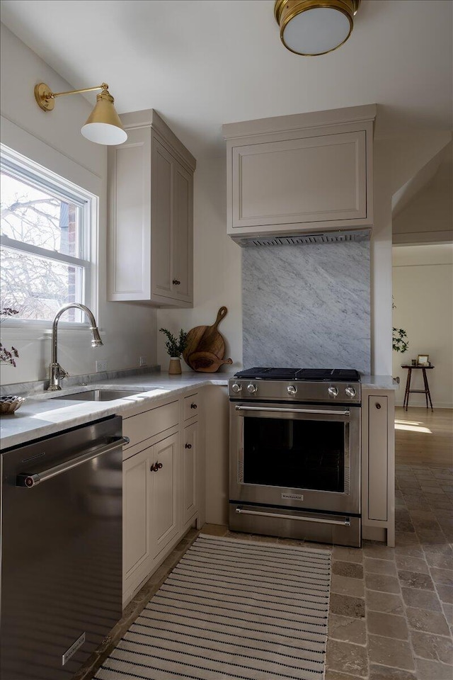 kitchen with light countertops, appliances with stainless steel finishes, stone finish floor, and a sink