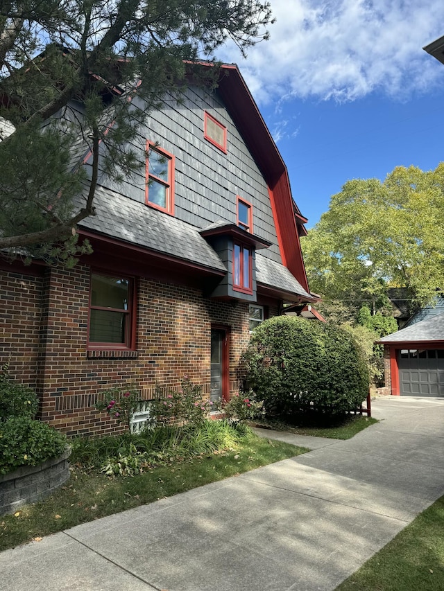 view of front facade with an outbuilding, brick siding, and a garage