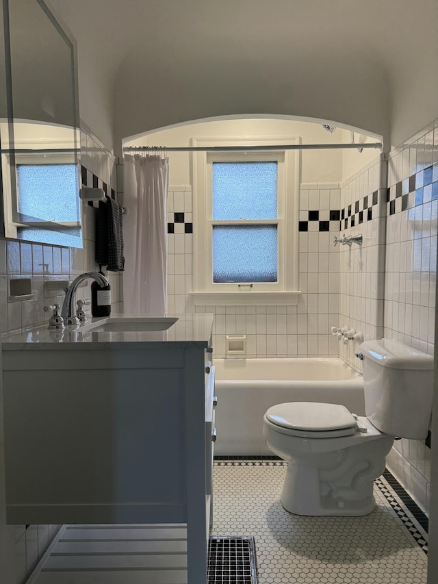 full bathroom featuring tile walls, shower / bathtub combination with curtain, toilet, vanity, and tile patterned floors