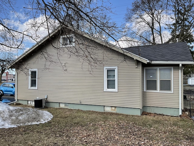 view of property exterior with central AC and roof with shingles