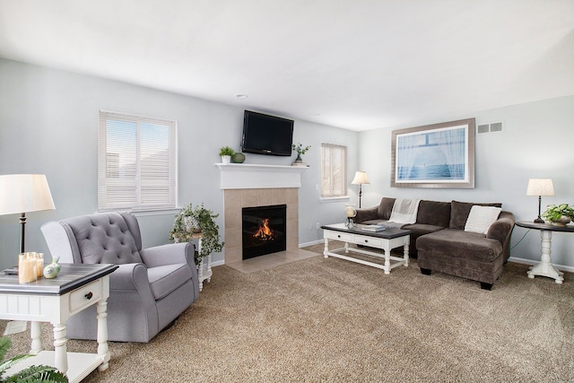 living room with carpet floors, baseboards, visible vents, and a tiled fireplace