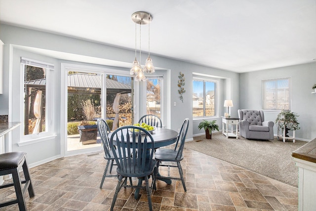 carpeted dining space with stone finish flooring and baseboards