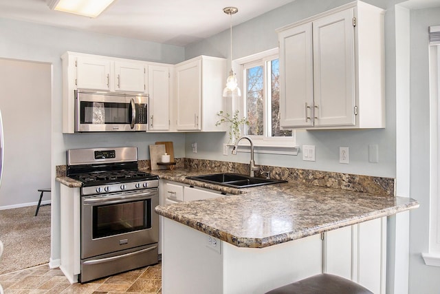 kitchen featuring a peninsula, white cabinetry, stainless steel appliances, and a sink