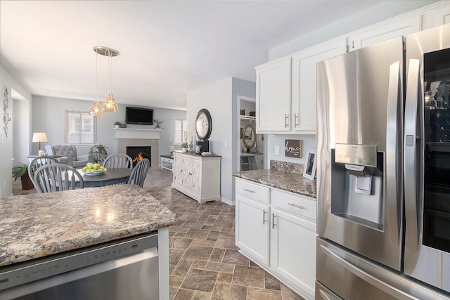 kitchen with stone finish flooring, a fireplace, white cabinetry, and stainless steel appliances