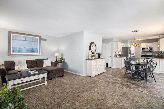 living room with baseboards, visible vents, a notable chandelier, and stone finish flooring