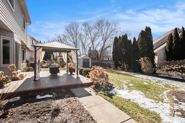 view of yard with a storage shed, an outdoor structure, fence, a gazebo, and a patio area