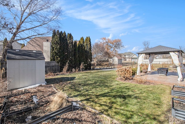 view of yard with an outbuilding, a patio, a fenced backyard, a gazebo, and a storage unit