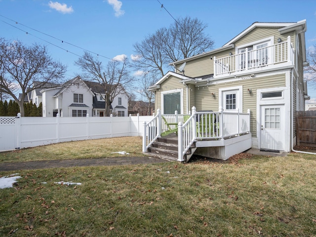 back of property with a fenced backyard, a yard, and a balcony