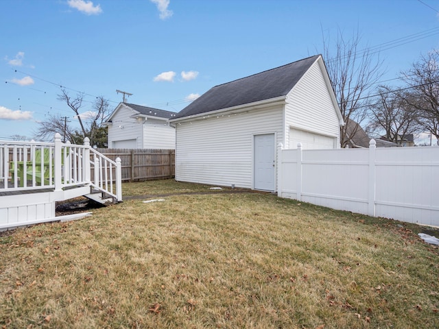 view of yard featuring an outbuilding, a fenced backyard, and a garage