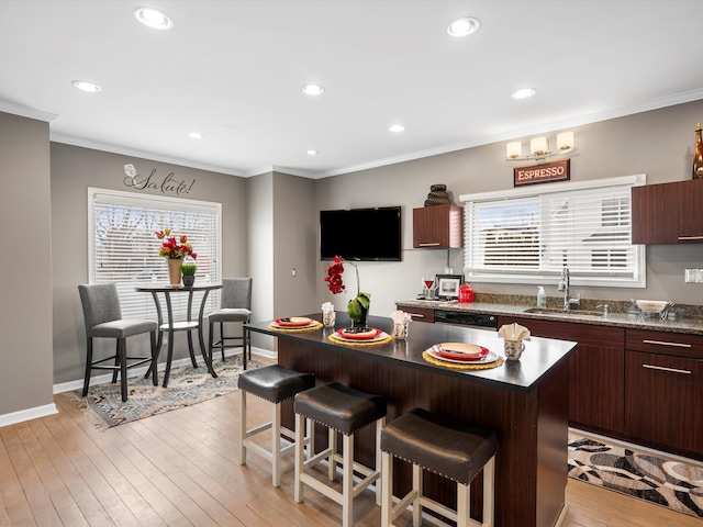 kitchen with ornamental molding, a breakfast bar, a sink, and light wood-style flooring