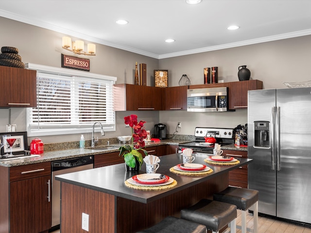 kitchen with a breakfast bar area, stainless steel appliances, a kitchen island, a sink, and ornamental molding