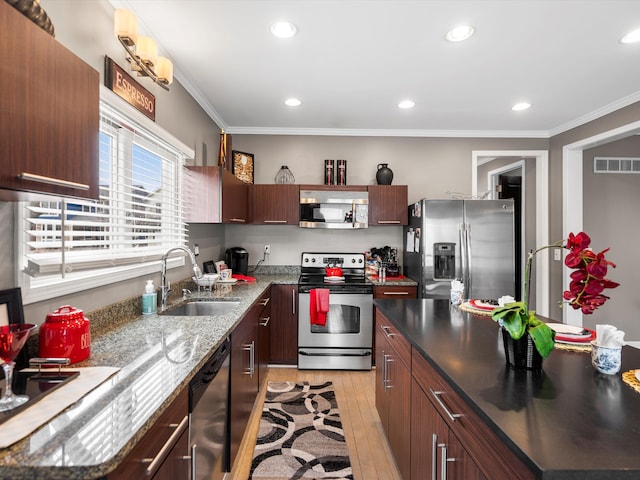 kitchen featuring appliances with stainless steel finishes, a sink, light wood-style floors, and crown molding