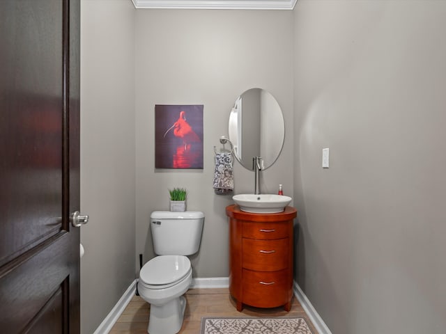 half bathroom featuring wood finished floors, vanity, toilet, and baseboards