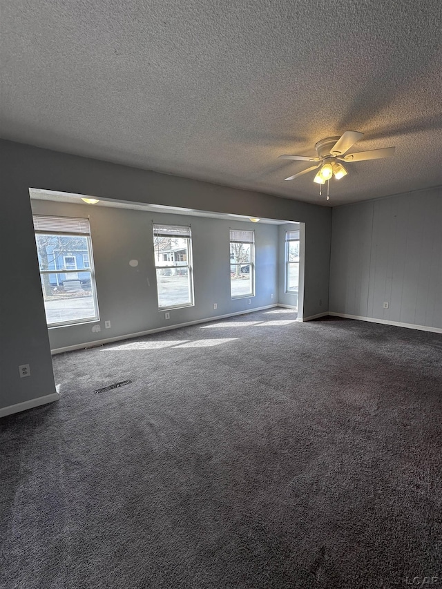 empty room with plenty of natural light, visible vents, and carpet flooring