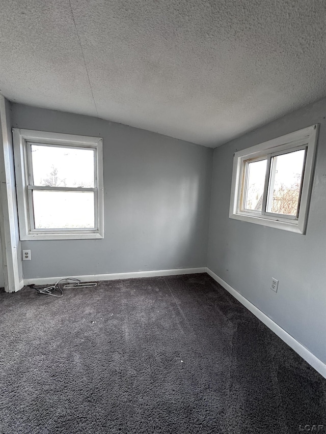 unfurnished room featuring dark carpet, a textured ceiling, and baseboards