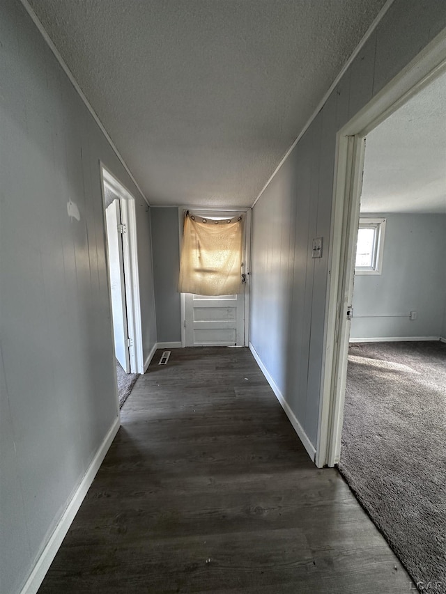 hall with a textured ceiling, baseboards, wood finished floors, and crown molding