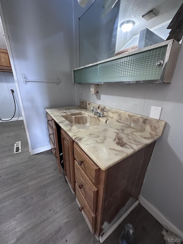 bathroom featuring visible vents, baseboards, wood finished floors, and vanity