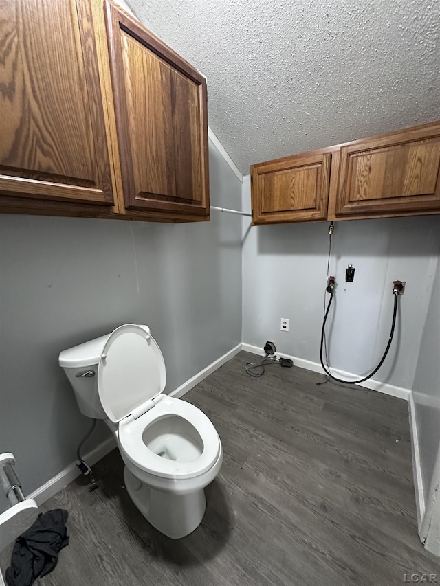 bathroom with a textured ceiling, wood finished floors, and baseboards