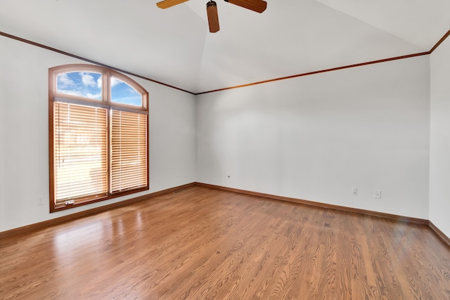 spare room with ceiling fan, baseboards, vaulted ceiling, light wood-type flooring, and crown molding