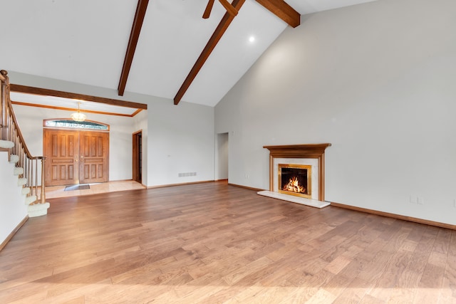 unfurnished living room with beam ceiling, visible vents, a high end fireplace, wood finished floors, and stairs