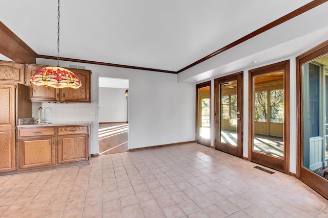 kitchen featuring visible vents, baseboards, light countertops, ornamental molding, and hanging light fixtures