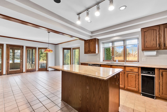 kitchen featuring light tile patterned floors, decorative backsplash, light stone counters, a center island, and a sink