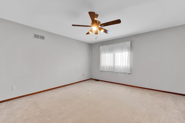 carpeted spare room featuring baseboards, visible vents, and a ceiling fan