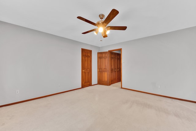 spare room with light carpet, a ceiling fan, and baseboards