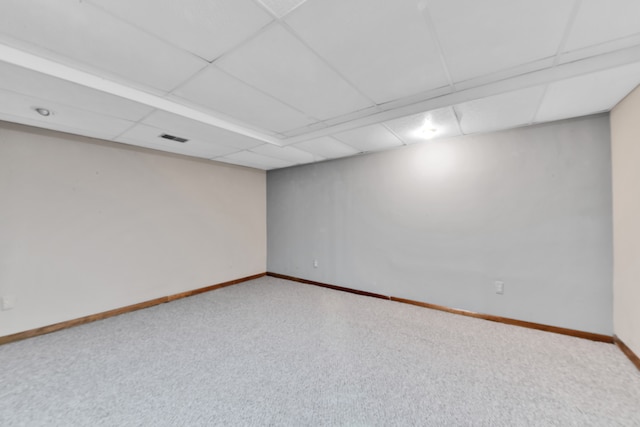 finished below grade area with a paneled ceiling, carpet, visible vents, and baseboards