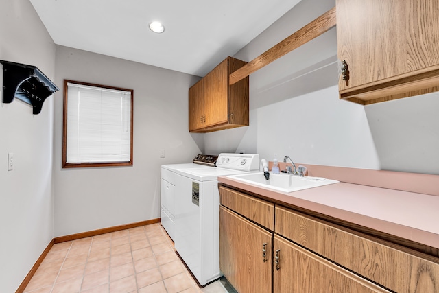 clothes washing area featuring washer and clothes dryer, light tile patterned floors, cabinet space, a sink, and baseboards